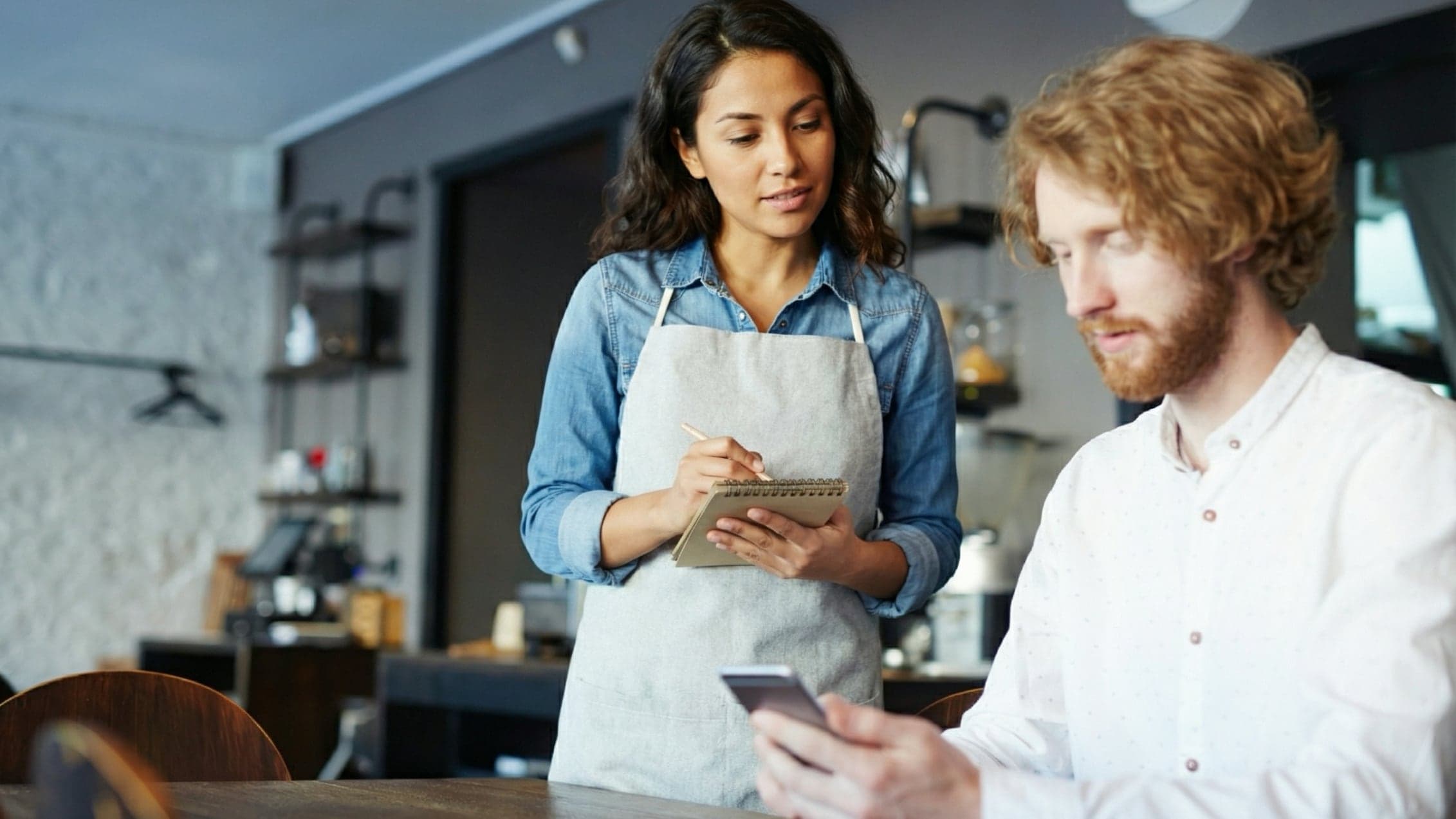 Waitress taking an order from a customer browsing menu on phone